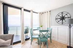 a dining room with a table and chairs and a balcony at Sunbird Sunsets in Panama City Beach