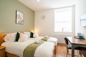 a bedroom with two beds and a desk and a window at Innovation House in Burnley