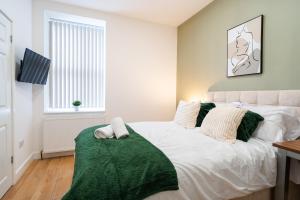 a bedroom with a bed with a green blanket on it at Innovation House in Burnley