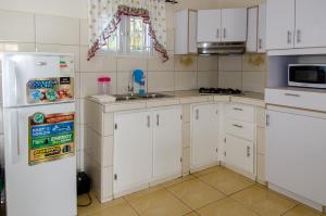 Una cocina con gabinetes blancos y un refrigerador blanco. en Tali & Tani Apartment, en Willemstad