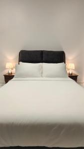 Paddy Villea Inn SPT Penang في Permatang Pauh: سرير أبيض كبير مع مصباحين على طاولتين