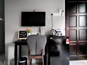 einen Schreibtisch mit einem Stuhl, einem Laptop und einem TV in der Unterkunft Paddy Villea Inn SPT Penang in Permatang Pauh