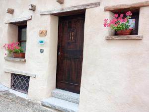 une maison avec une porte en bois et deux plantes en pot dans l'établissement B&B e Home Restaurant S'ispera Monolocale uso esclusivo, à Fonni