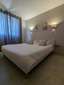 ein großes weißes Bett in einem Zimmer mit Fenster in der Unterkunft Fuzei Hôtel Lorient-Lanester in Lanester