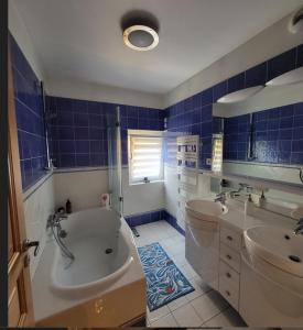 a blue tiled bathroom with a tub and a sink at Poésie en partage in Giromagny