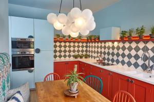 a kitchen with red cabinets and a wooden table with a potted plant at The Lark - High Style by the Roman Baths in Bath