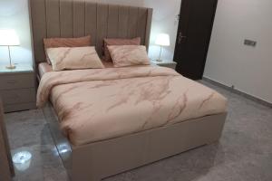 a bedroom with a large bed with pink sheets and pillows at luxurious Family Apartment in Karachi