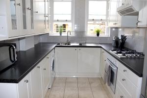 eine Küche mit weißen Schränken und schwarzen Arbeitsplatten in der Unterkunft Baywater - Central London in London