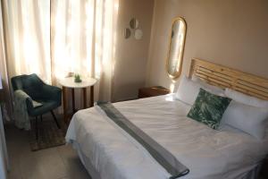 een slaapkamer met een bed, een stoel en een raam bij Unitrainview guest house in Pretoria