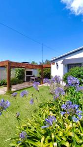 a garden with purple flowers in front of a house at Cabaña a pasos del lago in Tandil