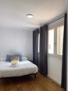 a bedroom with a bed with blue pillows and a window at Apartamentos Ceo ciudad in Ronda