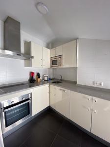 una cocina con armarios blancos y electrodomésticos de acero inoxidable en Apartamentos Ceo ciudad en Ronda
