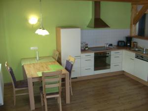 a kitchen with a table and chairs and a kitchen with green walls at Am Angerbach in Oberstaufen
