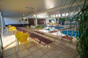 una piscina con mesas amarillas y sillas en un edificio en Apart Hotel Aguasol, en Termas del Daymán