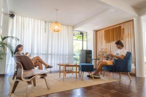 2 personas sentadas en sillas en una sala de estar en Apart Hotel Aguasol, en Termas del Daymán