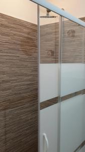 a glass shower door with a wooden wall at Appartamento nel cuore di Varese in Varese