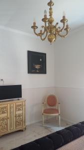 a living room with a chandelier and a chair at PALAZZO NOVECENTO Rooms in Lecco