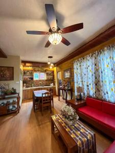 a living room with a red couch and a ceiling fan at Dahilayan Comfy Cabin in Manolo Fortich