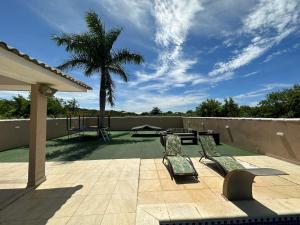 a patio with two benches and a table and a palm tree at Casa Búzios - Temporada in Búzios