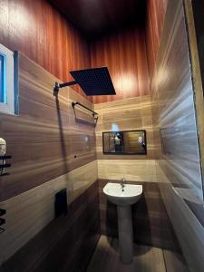 a bathroom with a white sink and a mirror at Dahilayan Comfy Cabin in Manolo Fortich