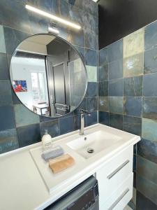 een badkamer met een wastafel en een spiegel bij Vue sur la place des Halles, Art Apparts in Béziers