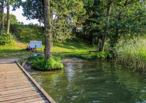 a river with a wooden walkway next to a sign at Domki Piękna Góra in Giżycko