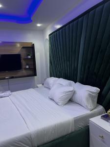 a bedroom with a large bed with a green headboard at Seaview Palace in Lekki