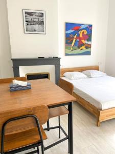 Pokój z 2 łóżkami, stołem i biurkiem w obiekcie Vue sur la place des Halles, Art Apparts w Béziers