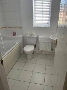 a bathroom with a toilet and a tub and a sink at 5 Holborn Spacious Home in Redhill