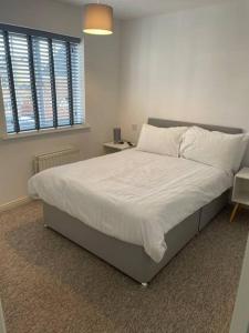 um quarto com uma cama grande com lençóis brancos e almofadas em 5 Holborn Spacious Home em Redhill