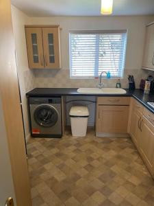 een keuken met een wastafel en een wasmachine bij 5 Holborn Spacious Home in Redhill