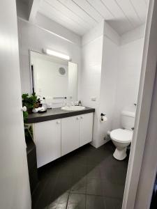 a white bathroom with a sink and a toilet at Villa 29 Beach Spa Pool in Mandurah