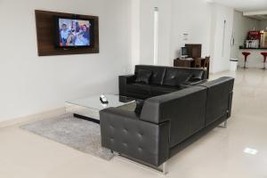 a living room with a black leather couch and a table at Big Hotel in Araguari