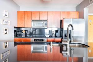 a kitchen with stainless steel appliances and wooden cabinets at Brickell Center w/City & Bay View + FREE Parking! in Miami