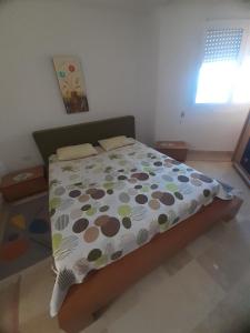 1 dormitorio con 1 cama con un edredón colorido en Afnane 3 en Chott Meriem