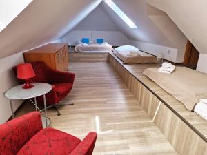 a attic room with two beds and two chairs at Apartmány Comfort in Střílky