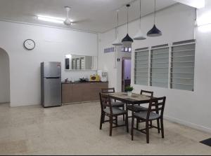 a kitchen with a table and chairs and a refrigerator at Amilite Villa in Gelugor