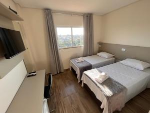 Cette chambre comprend 2 lits et une fenêtre. dans l'établissement Hotel Gold Ville, à Siqueira Campos
