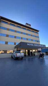 un bâtiment d'hôtel avec une voiture garée dans un parking dans l'établissement Hotel Gold Ville, à Siqueira Campos