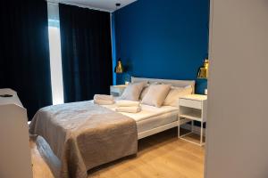 ein Schlafzimmer mit einem Bett und einer blauen Wand in der Unterkunft Waveside Apartments and SPA Dziwnów in Dziwnów