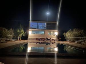 une maison avec une piscine en face de celle-ci la nuit dans l'établissement Chez Jamal, à Kasba Aït Youdi