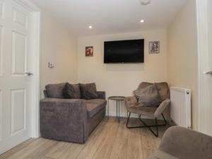 a living room with a couch and a chair and a television at Badgers Sett in Lydney