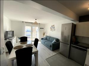 uma cozinha e sala de estar com uma mesa e um sofá azul em Appartement Stella-Plage em Cucq