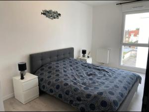 um quarto com uma cama com um edredão azul e uma janela em Appartement Stella-Plage em Cucq