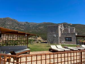 a deck with lounge chairs and a building with mountains at VILLA DEMETRA in Kissamos