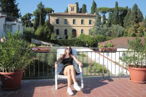een vrouw in een stoel op een balkon voor een huis bij Villa Gelsomino Garden in Florence