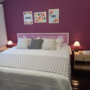 a bedroom with a large bed with a purple wall at Apart Coração de Búzios in Búzios