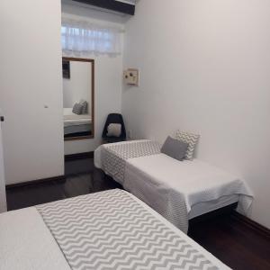 a white room with two beds and a mirror at Apart Coração de Búzios in Búzios