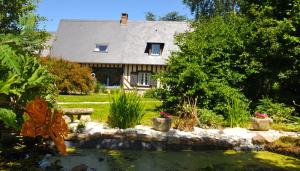 a house with a pond in the yard at Le Bois des Pierres in Conteville