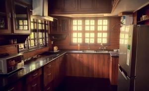 a kitchen with wooden cabinets and a sink and a refrigerator at Beautiful Beach Front Villa - Beach Castle Homestay in Udupi